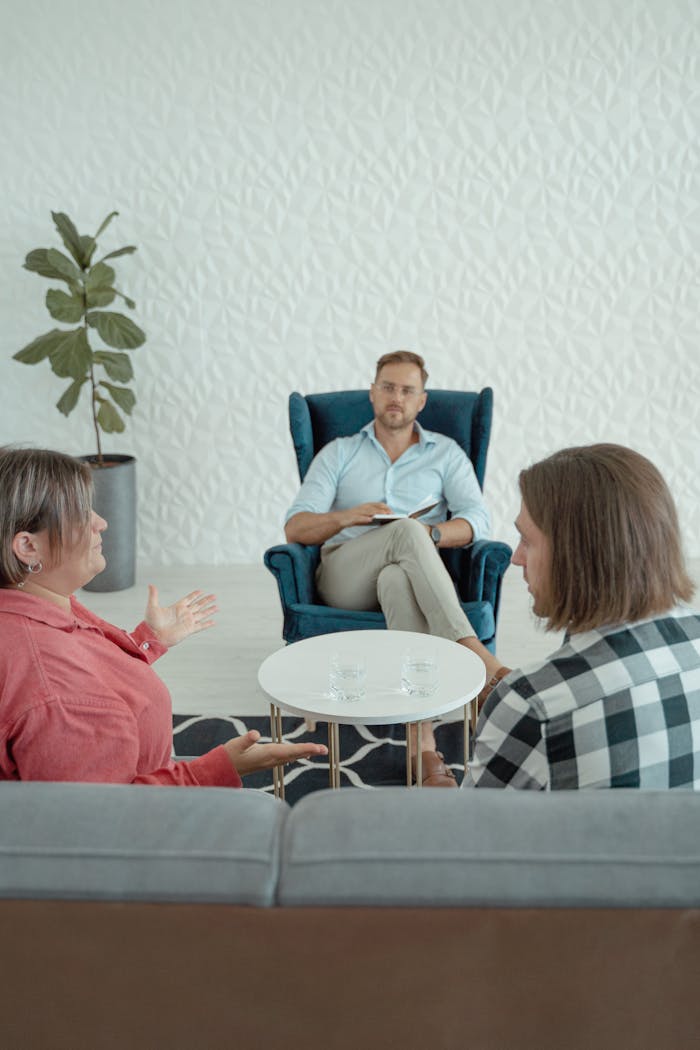 A marriage counselor listens to a couple discussing marital issues in a calm office setting.